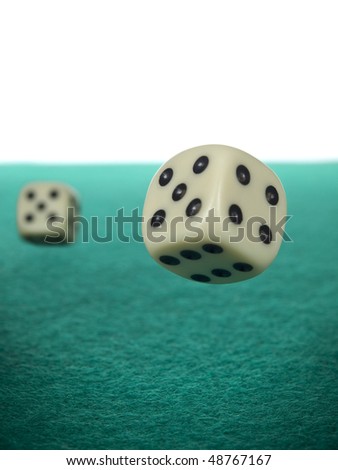 A pair of dices rolling over a green felt.