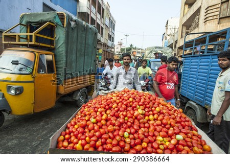 BANGALORE, INDIA - May 13, 2014: An unidentified vegetable seller pushes a cart full of tomatoes through the crowd on his way to the busy city vegetable market