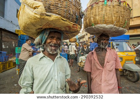 BANGALORE, INDIA - May 13, 2014: Two old men carry vegetables in baskets on their way to the busy city market