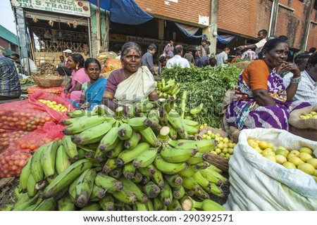 BANGALORE, INDIA - May 13, 2014: a group of women sit below a truck selling fresh vegetables stall in the busy city market