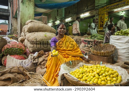 BANGALORE, INDIA - May 13, 2014: a woman sells fresh limes in the city market early in the morning, other vendors in the background