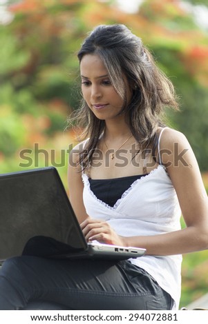Beautiful young Indian business woman with a laptop working outdoors.