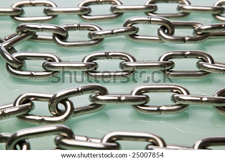 Multiple strands of chrome chain on a glass surface