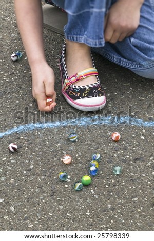 Young girl playing marbles within a chalk ring