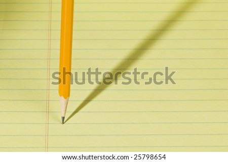 Pencil in writing position on a pad of yellow paper