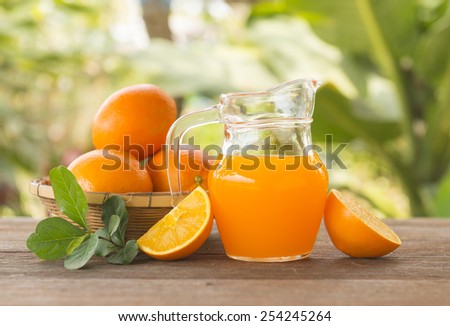 Orange juice is placed on a wooden table with natural light.