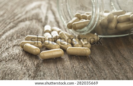 Herb capsule (moringa oleifera) spilling out of a bottle.
