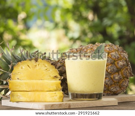 Pineapple juice and pineapple slice placed on a wooden table.