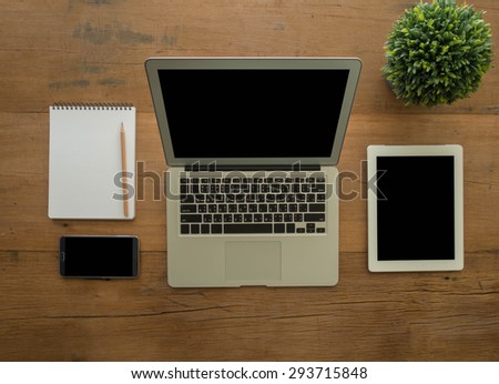 Open laptop computer with  tablet , smartphone , notebook on wooden desk. top view