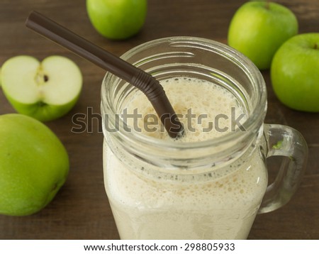 green apple smoothie in glass on wooden background