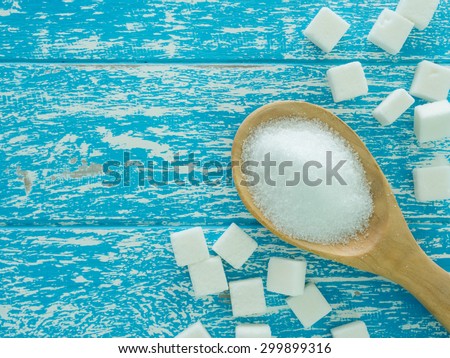 sugar on wooden spoon and cube sugar on wooden background