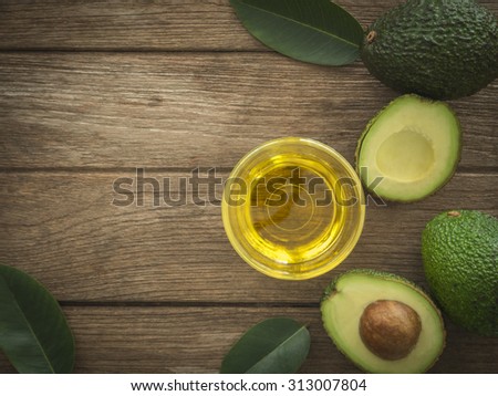 glass bowl of avocado essential oil with fresh avocado fruit closeup