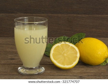Fresh lemon juice in a glass placed on a wooden floor.