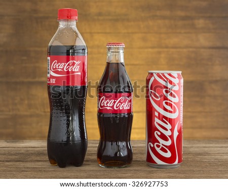 Bangkok, Thailand - Oct 13, 2015 : Coca-Cola soft drinks on the table with background with dark wood panels. Coca-Cola brand is one of the world famous soft drinks chains from USA.