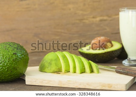 avocado and Sliced avocado slices on wooden board.