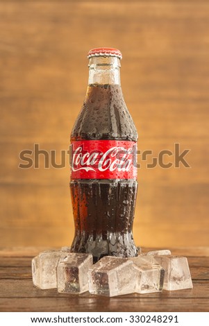 Bangkok, Thailand - Oct 13, 2015 : Coca-Cola soft drinks on the table with background with dark wood panels. Coca-Cola brand is one of the world famous soft drinks chains from USA.