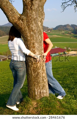 Couple hugging tree and making a heart.