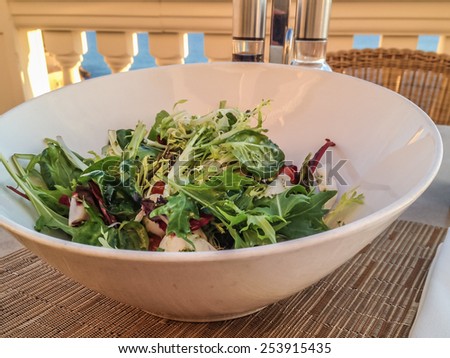Fresh mixed salad in a white bowl on a restaurant table \
Fresh mediterranean salad in a white bowl on table with balsamico and olive oil in background. Healthy food for vegetarians and low carb diet