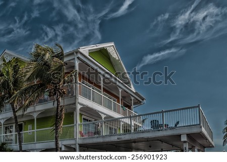 Architectural building Palms in motion hurricane season image retro filtered \
Street view of Florida Style residential building against dark sky before tropical hurricane thunderstorm