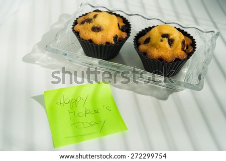 Aerial View Happy Mother\'s Day with cupcakes and text message \
Appreciation green sticky note greeting card with butter pastry cakes with raisins on vintage glass plate, white natural light background