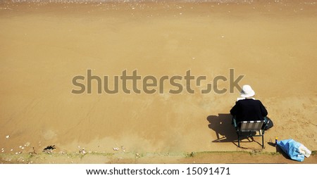 Old lady reading on a sandy beach