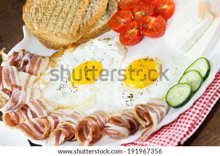 breakfast of eggs, bacon, cheese, tomato