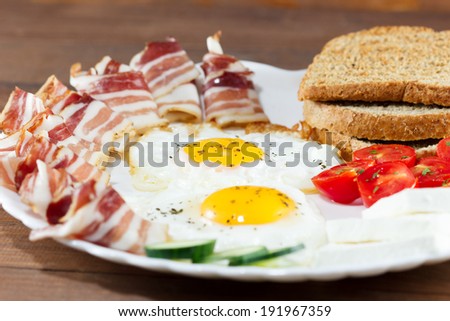 Breakfast including  bread, eggs, bacon, cheese, tomato