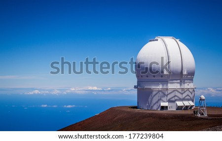 Observatory dome at the peak of Mauna Kea volcano, Hawaii. Telescope structure on volcano top above the main cloud layert.