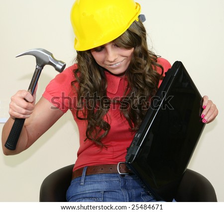 A pretty girl fixes her laptop with a large hammer
