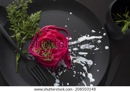 Spaghetti roses, black place setting, pasta dyed with food coloring on rustic wooden table black