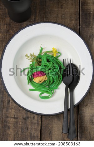 Green spaghetti, dyed with food coloring on rustic wooden table