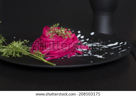 Spaghetti roses, black place setting, pasta dyed with food coloring on rustic wooden table black