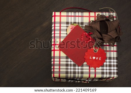 presents wrapped in checkered paper and dotted ribbon with red  label on wooden background