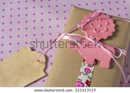 Gift wrapped in recyclable paper, ribbons and label flower on pink dotted background