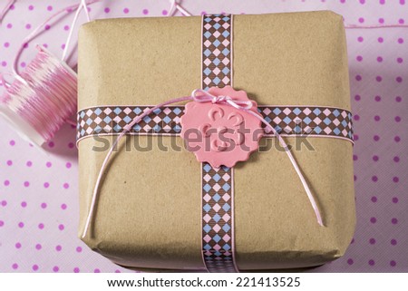 Gift wrapped in recyclable paper, ribbons and label flower on pink dotted background