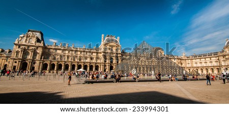 PARIS, FRANCE - APRIL 14, 2013: Tourists in the Louvre\'s central courtyards with the Louvre pyramid and palace. The Louvre is the world\'s most visited museum