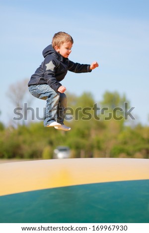 Young boy jumping on green and yellow trampoline.