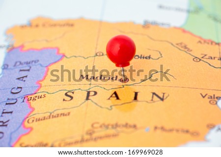 Round red thumb tack pinched through city of Madrid on Spain map. Part of collection covering all major capitals of Europe.