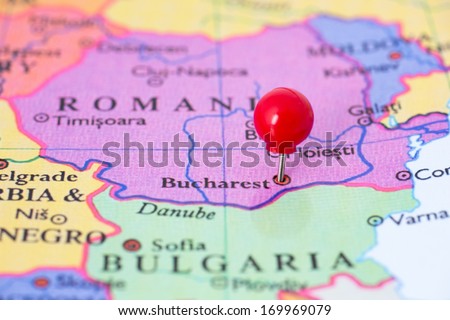 Round red thumb tack pinched through city of Bucharest on Romania map. Part of collection covering all major capitals of Europe.