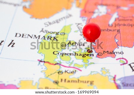 Round red thumb tack pinched through Copenhagen on Denmark map. Part of collection covering all major capitals of Europe.
