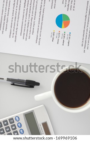 An office desk seen from above. Paper, pen, coffee and calculator.