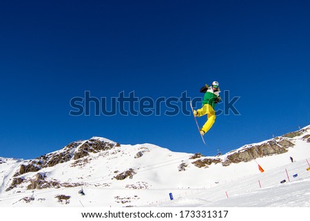 Snowboarder in colorful clothing performing a bold move in snow park. Trademarks have been removed.