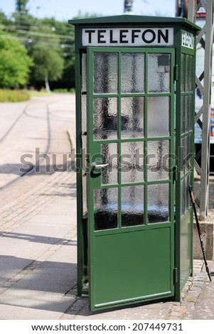 Classical old green phone booth with open door.