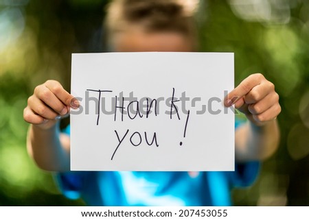 Blurred boy holding a piece of paper with the words Thank You in front of her.