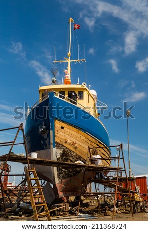 Medium-sized boat undergoing maintenance and repairs while in dock.