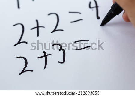 Close-up of simple math written on white piece of paper.