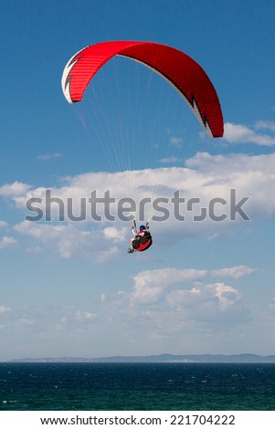 Single paraglider hovering in the sky on a sunny day.