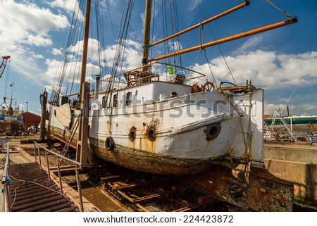 Large old sailing boat undergoing serious repair work while docked on the quay.
