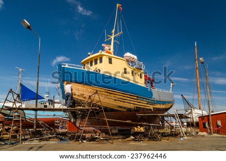 Medium-sized boat undergoing maintenance and repairs while in dock.