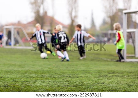 Young kids during a boys soccer match on green soccer pitch.